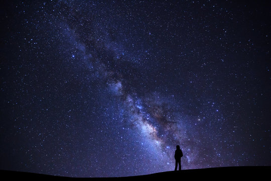 Landscape with milky way galaxy, Starry night sky with stars and silhouette of a standing man on high mountain.