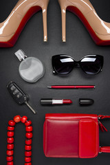 Woman accessories, shoes, bag, jewelry, cosmetics, pen in red color and other objects on leather...