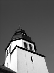 Kirchturm der katholischen Pfarrkirche Sankt Johannes Baptist in Schloß Holte-Stukenbrock bei Gütersloh in Ostwestfalen-Lippe, fotografiert in neorealistischem Schwarzweiß