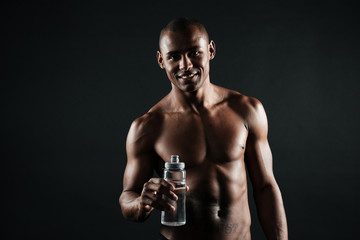 Fototapeta na wymiar Portrait of smiling young afro american sports man, holding bottle of water