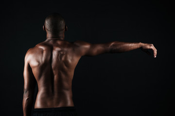 Back view photo of half-naked muscular sports man, with right hand up