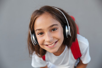 Close up image of smiling brunette schoolgirl listening music