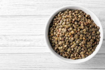 Bowl with black lentils on wooden background
