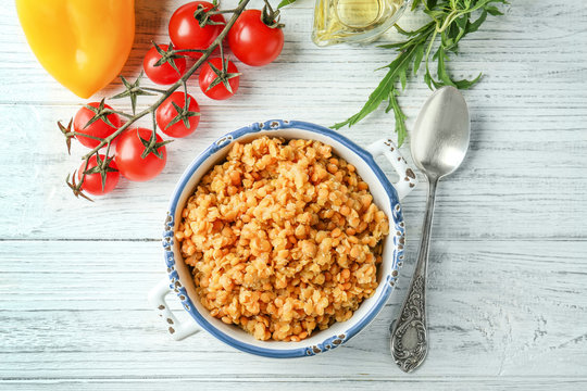 Casserole with boiled lentils on wooden background