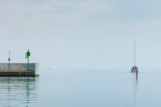 Fototapeta Small yacht swimming to harbor