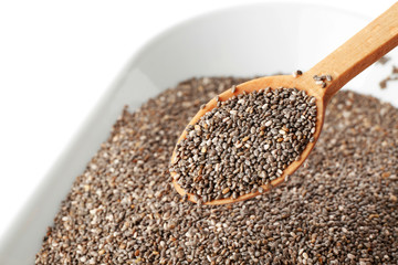 Bowl and spoon with chia seeds on white background, closeup