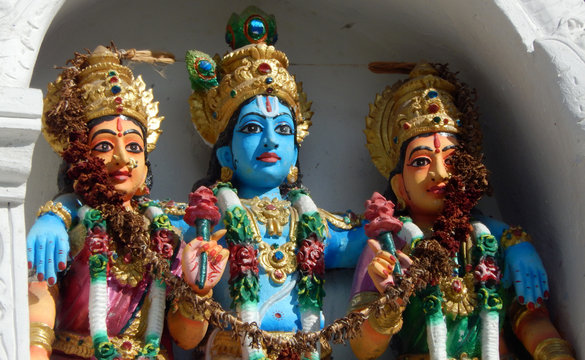 Statue of Hindu God Sri Krishna with consorts on the wall of a temple 