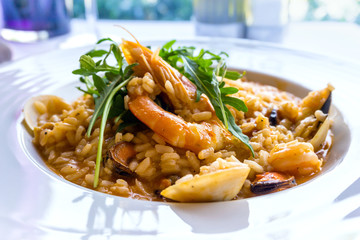 Tasty risotto with Shrimp, fresh herbs vegetables on a white plate