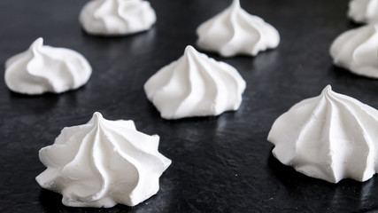 Sweet white meringue is isolated on a dark background.