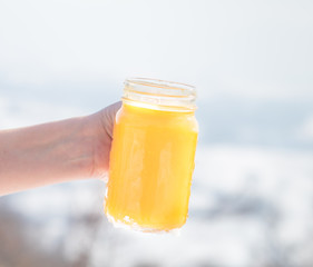 Winter vitamins immunity concept . Hand holding jar with Freshly squeezed Orange citrus juice for health on winter background.