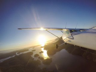 Airplane flying across the beautiful Canadian Landscape during a vibrant summer sunset. Taken on the West Coast near Tofino, Vancouver Island, British Columbia, Canada. Concept: Adventure, Travel

