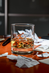 Scotch with ice on the desktop among contracts and documents