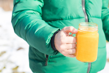 Winter vitamins immunity concept . Hand holding jar with Freshly squeezed Orange citrus juice for health on winter background.