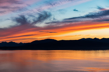 Naklejka na ściany i meble Alaskan coastline sunset with mountain silhouette
