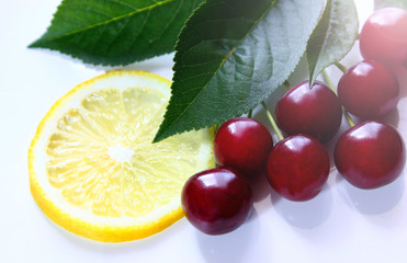 Sweet fresh cherries with green leaves background, close-up on a white rustic table. Healthy food.