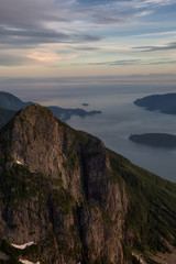 Aerial view of the North Shore Mountain, Mount Harvey, with Howe Sound in the background. Taken North of Vancouver, British Columbia, Canada, during a vibrant summer sunset.
