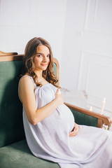 Young happy pregnant woman sitting on sofa