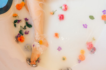 beautiful woman leg in the milk bath with flowers