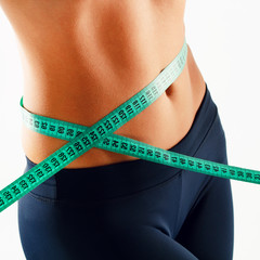 Woman measuring her waist over white background. Wellness concept.