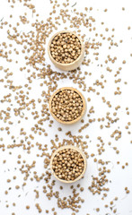 Organic Dried coriander seeds (Coriandrum sativum) in a wooden jar, selective focus, on white background