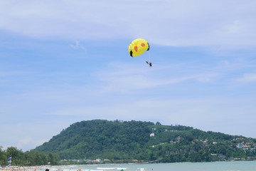 Parachute floats in the sky above the green mountains.