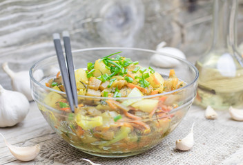 Homemade nutritional vegetable ragout in glass plate bowl on rustic old wooden table. Vegan or vegetarian food diet. Selective focus.