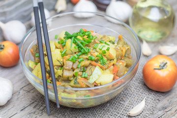 Homemade nutritional vegetable ragout in glass plate bowl on rustic old wooden table. Vegan or vegetarian food diet. Selective focus.