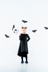 Little girl witch in black dress over magical accessories. Halloween, the studio evening.
