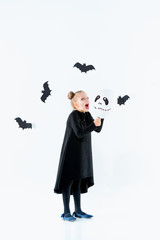 Little girl witch in black dress over magical accessories. Halloween, the studio evening.
