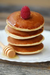Delicious pancakes with raspberries and honey in a bowl 