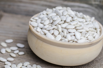 Protein albumen source. Pile of Vegetable vegan vegetarian healthy nourishing nutritional meal white kidney haricot lima beans in wooden rural bowl on wooden rustic background. Phaseolus lunatus