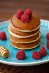 Delicious pancakes with raspberries and honey in a bowl 