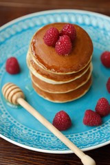 Delicious pancakes with raspberries and honey in a bowl 