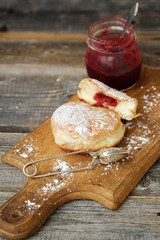 Delicious fresh donuts with cherry jam on the table