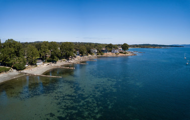 Aerial panoramic view of luxury homes in front of beautiful sandy beach on Pacific Coast. Taken in Victoria, Vancouver Island, British Columbia, Canada.