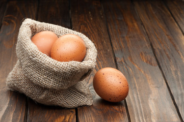 chicken eggs in burlap sack on wooden background