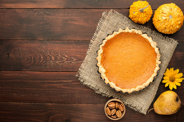 pumpkin homemade pie at wooden background arranged with food ingredients top view