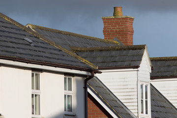 Modern town house roof with slate tiles, chimney and white dormer window
