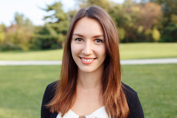 Fototapeta premium Closeup portrait of beautiful smiling young European Caucasian woman with red hair and brown eyes. Business lady outside looking in camera smiling.