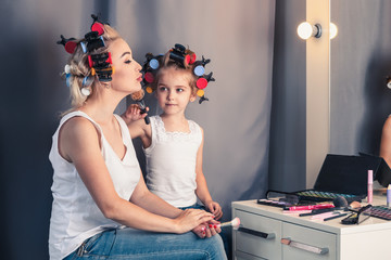 Mother and her child girl are doing your makeup and having fun n