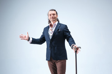 The mature barded man in a suit holding cane.