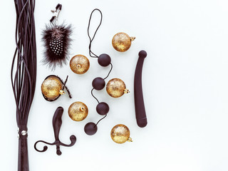 Various black sex toys and golden christmas balls are on a light background. Image for the festive...
