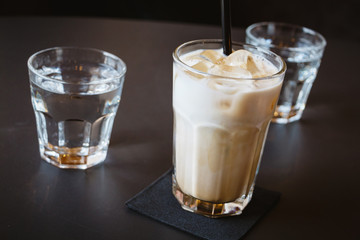 Glass of water and iced coffee or latte on a wooden table