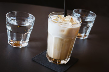Glass of water and iced coffee or latte on a wooden table