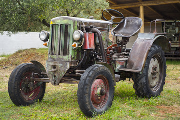 Retro tractor in green summer park.