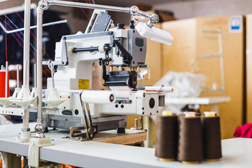 Professional overlock sewing machine. Equipment for edging, hemming or seaming clothes at tailors shop.