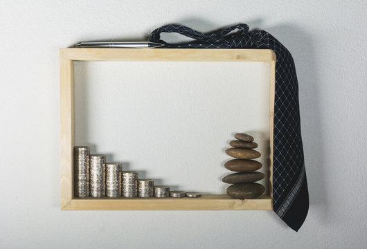 stack coin with pen and necktie in wooden frame on white wall background. Financial and saving concept.
