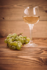 Glass of white wine and grapes on rustic wood table