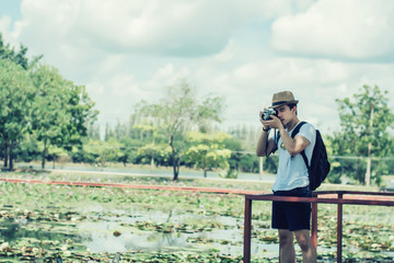 Young man tourists shooting vintage camera and backpack, shooting style, travel style in the park.