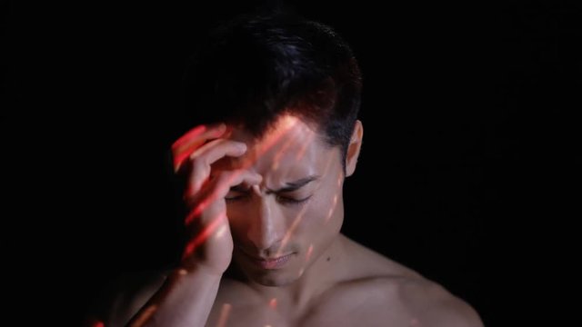 Light projected onto man's face indicating brain activity or migraine